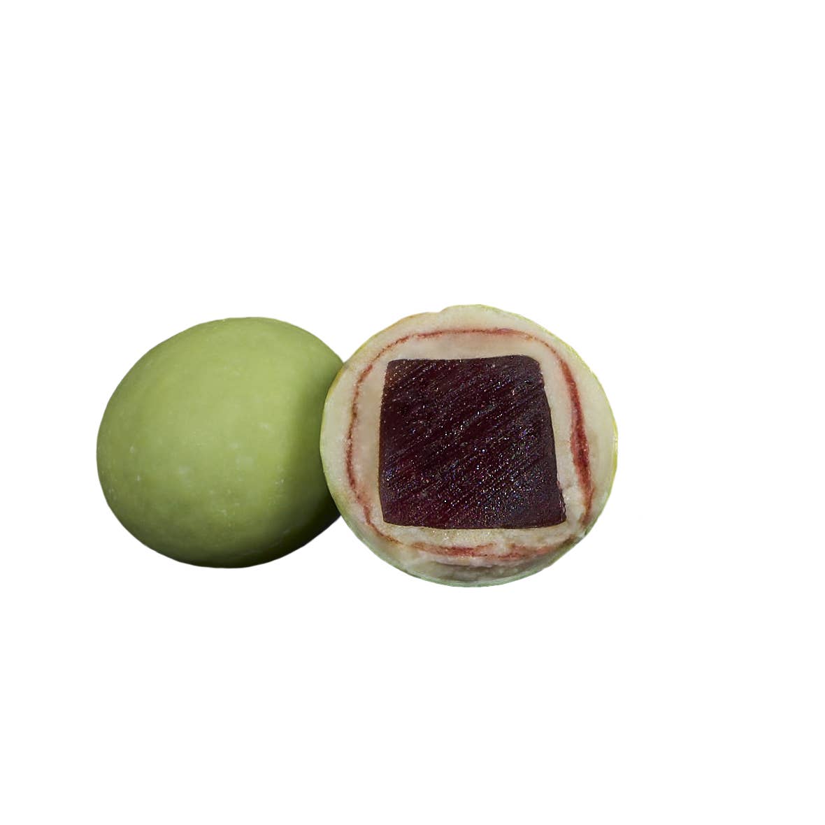 Two green mochi balls, one whole and one split to show red bean paste, sit beside a piece of Lakrids: Sour Strawberry Danish Gourmet Licorice Limited Edition by Bulow (4.41 oz) for a unique flavor pairing.