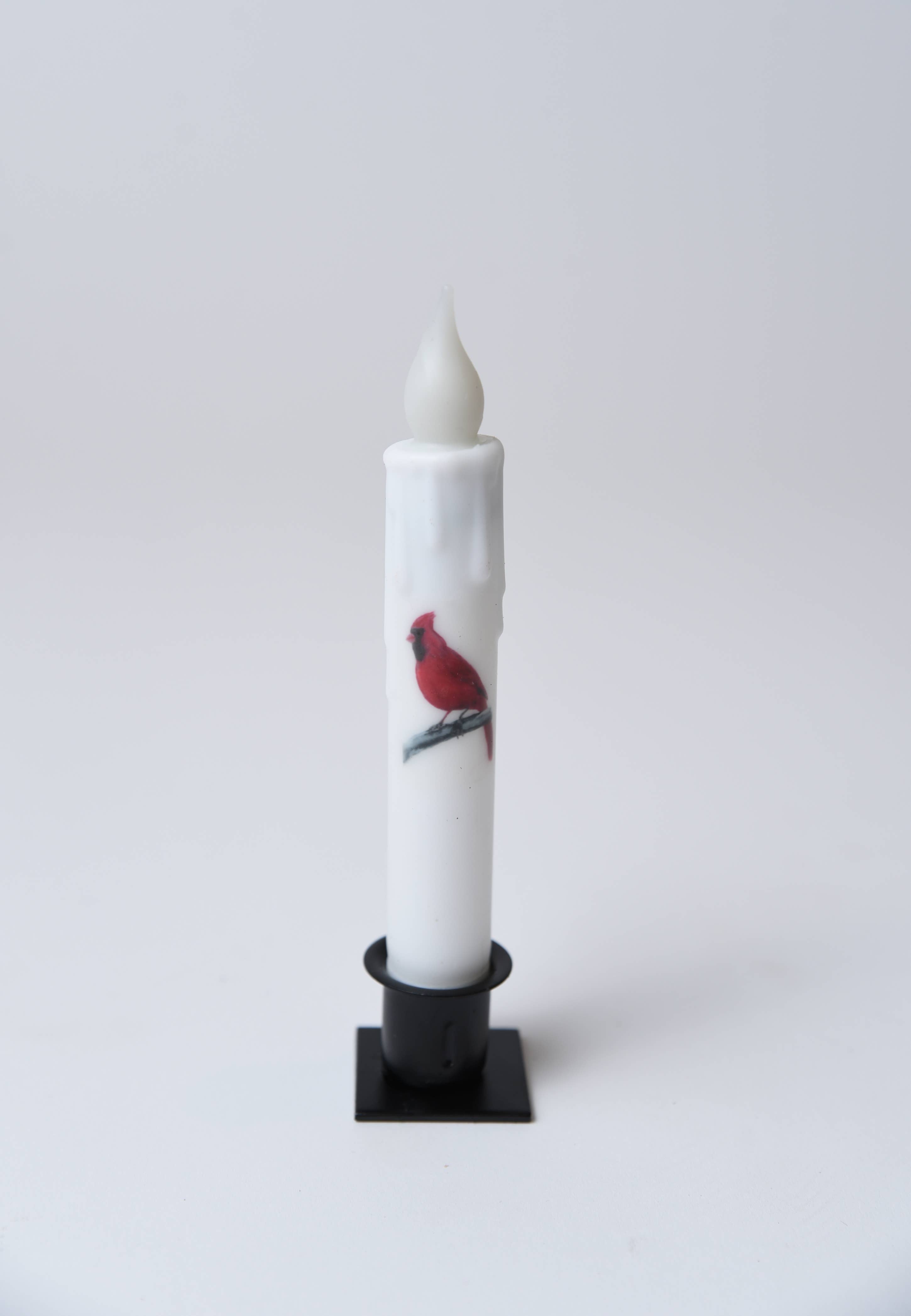 The Candle: Cardinal LED Timer Taper Candle is a 7" white LED taper with a faux flame in a black holder, featuring an illustration of a red cardinal perched on a branch.