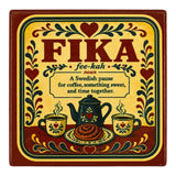 Square coaster featuring the word FIKA, a definition, a coffee pot, mugs, and a cinnamon bun, all decorated in traditional Swedish-style floral motifs.
