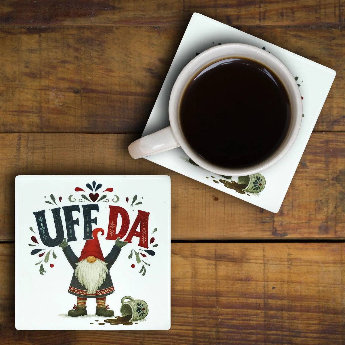 Square Scandinavian ceramic coaster with a Nordic gnome and the text UFF DA next to a matching coaster with black coffee.
