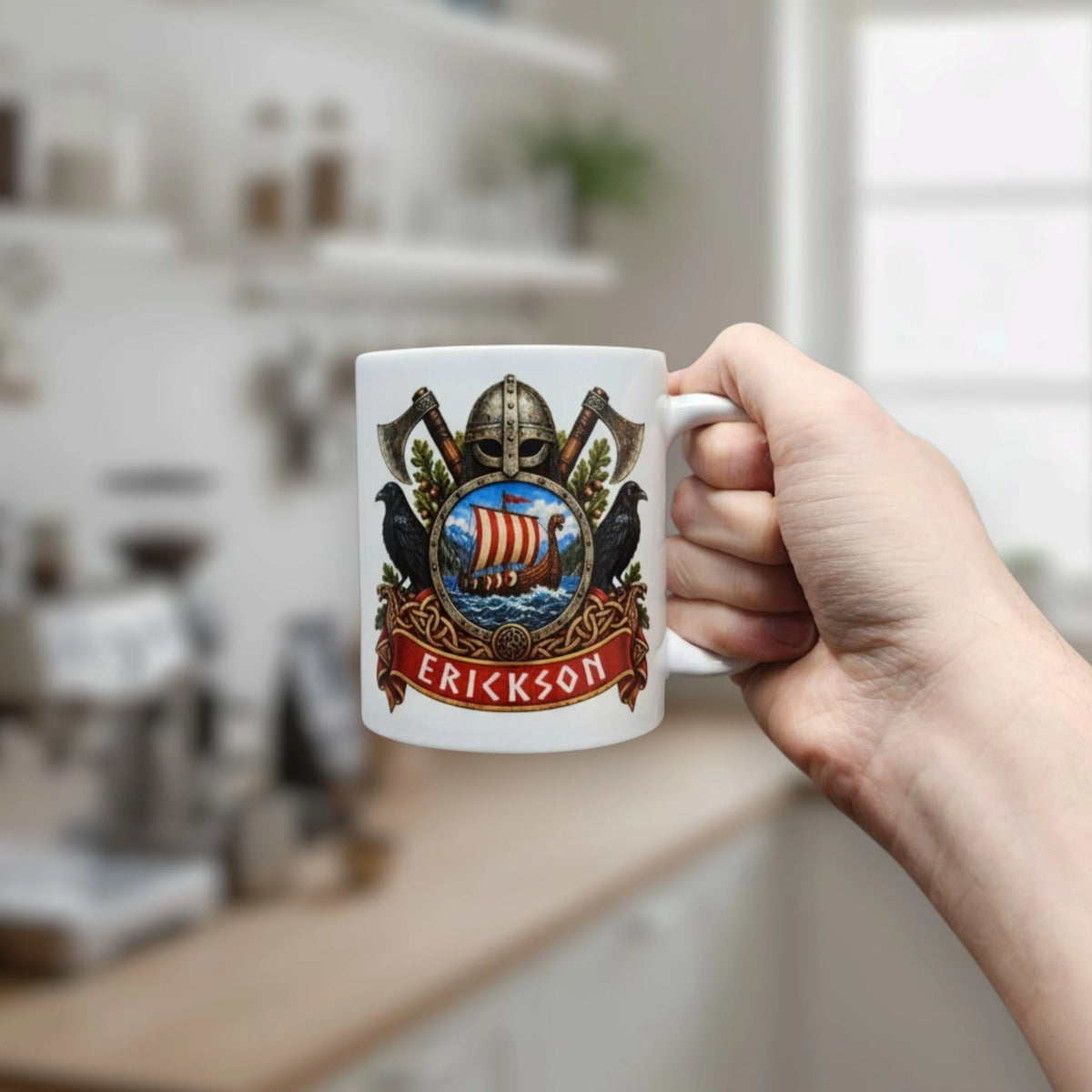 A hand holds a Viking-themed mug decorated with a ship, helmet, axes, ravens, and the name Erickson in a kitchen.