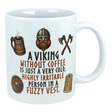 Ceramic mug with Nordic Viking art, featuring an axe and helmet illustration, and the text: “A Viking without coffee is just a cold, irritable person in a fuzzy vest.”.