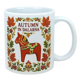 White ceramic mug featuring leaves, flowers, a red Swedish Dala horse, and the text “AUTUMN IN DALARNA” in Scandinavian folk art style.