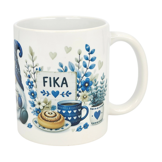 The Nordic Wholesale Mug: Blue Tomte Gnome Fika Ceramic Mug (11 oz) features blue and gray Scandinavian Tomte gnome designs with flowers, a cinnamon roll, coffee cup, and a “FIKA” sign surrounded by hearts and leaves.