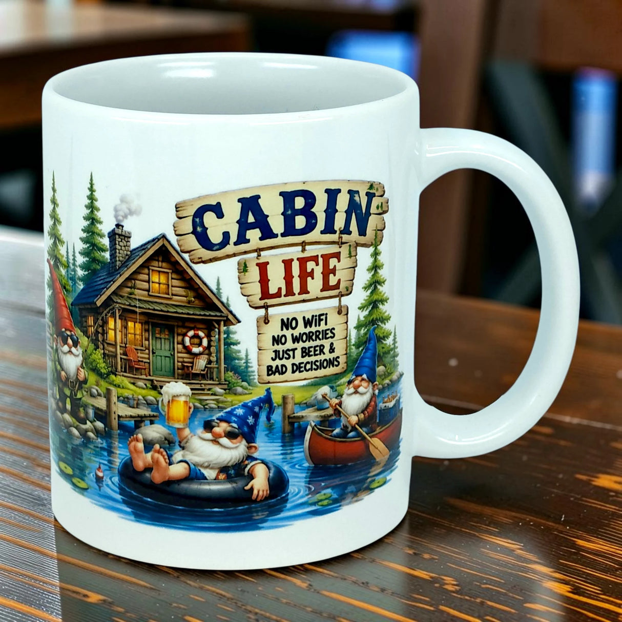 Start your day with the Mug: Cabin Life Gnomes Ceramic Coffee Mug (11 oz) from Nordic Wholesale, featuring whimsical cartoon gnomes unwinding by a cozy cabin and tranquil lake. This charming ceramic mug celebrates the simple pleasures of Cabin Life—no WiFi, no worries, just beer & bad decisions.