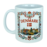 The Nordic Wholesale Mug: Denmark Nyhavn Ceramic Mug (11 oz Capacity) is a white Danish heritage mug showcasing DENMARK, a red Danish flag, floral accents, and detailed illustrations of Copenhagen’s vibrant Nyhavn harbor along with the iconic Little Mermaid statue.