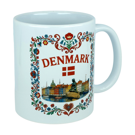 The Mug: Denmark Nyhavn Ceramic Mug (11 oz Capacity) by Nordic Wholesale is a white ceramic mug featuring colorful floral designs, the word "DENMARK," the Danish flag, and delightful illustrations of famous Danish landmarks such as Nyhavn harbor and the iconic Little Mermaid statue.