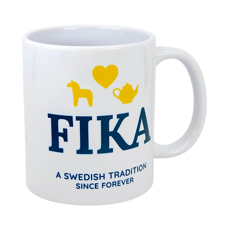 A white 11 oz ceramic mug from Nordic Wholesale featuring the word “FIKA,” yellow icons of a horse, heart, and teapot, with “A Swedish Tradition Since Forever” printed below.