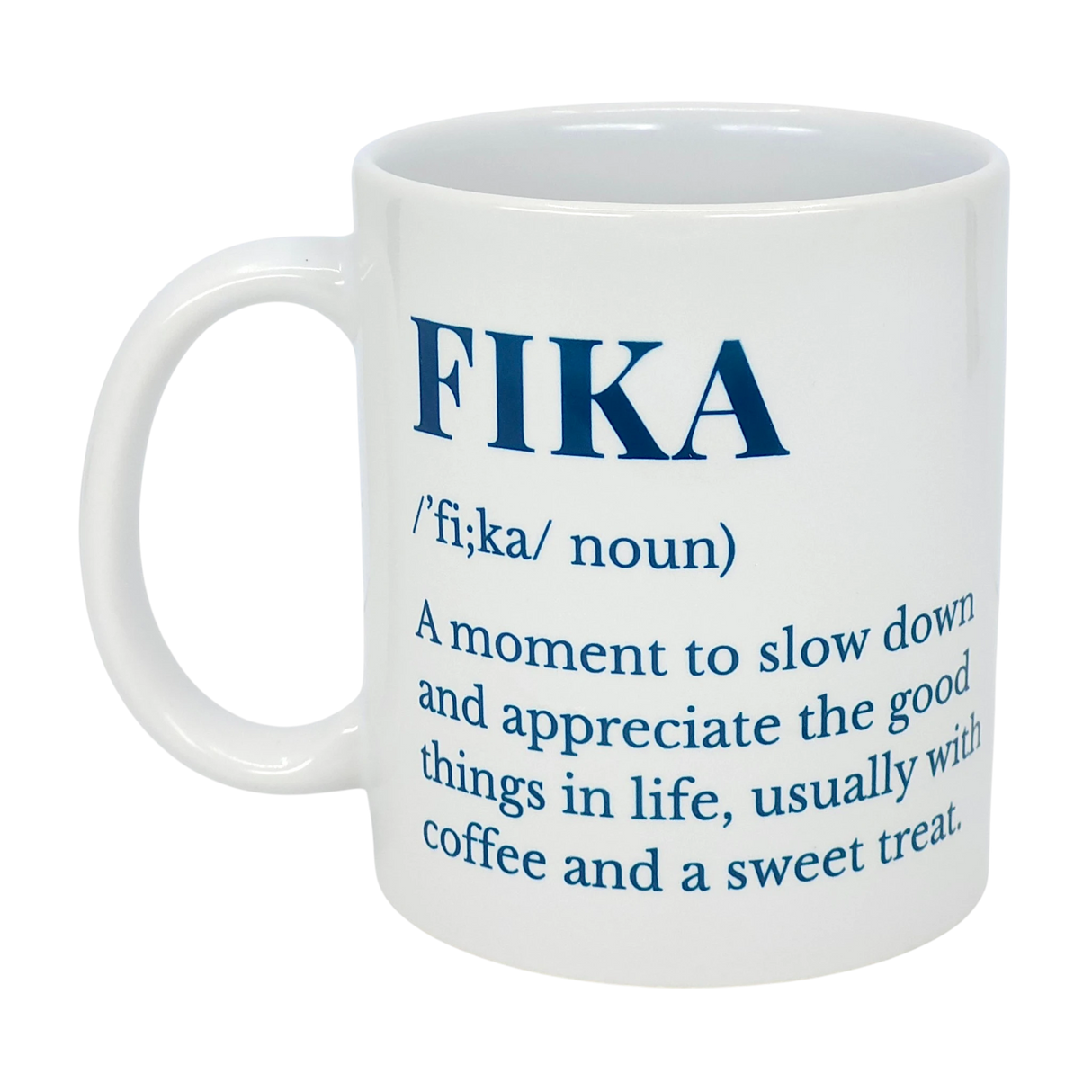The White Ceramic Fika Definition Mug (11 oz) from Swedish Gift Store features blue text explaining the Swedish "Fika" tradition—pausing to enjoy coffee, a sweet treat, and life's good moments.
