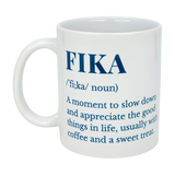 The White Ceramic Fika Definition Mug (11 oz) from Swedish Gift Store features blue text explaining the Swedish "Fika" tradition—pausing to enjoy coffee, a sweet treat, and life's good moments.