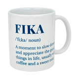 The Swedish Gift Store's White Ceramic Fika Definition Mug (11 oz) features blue text defining FIKA as a noun—a moment to slow down and savor the good things, often enjoyed with coffee and a sweet treat.