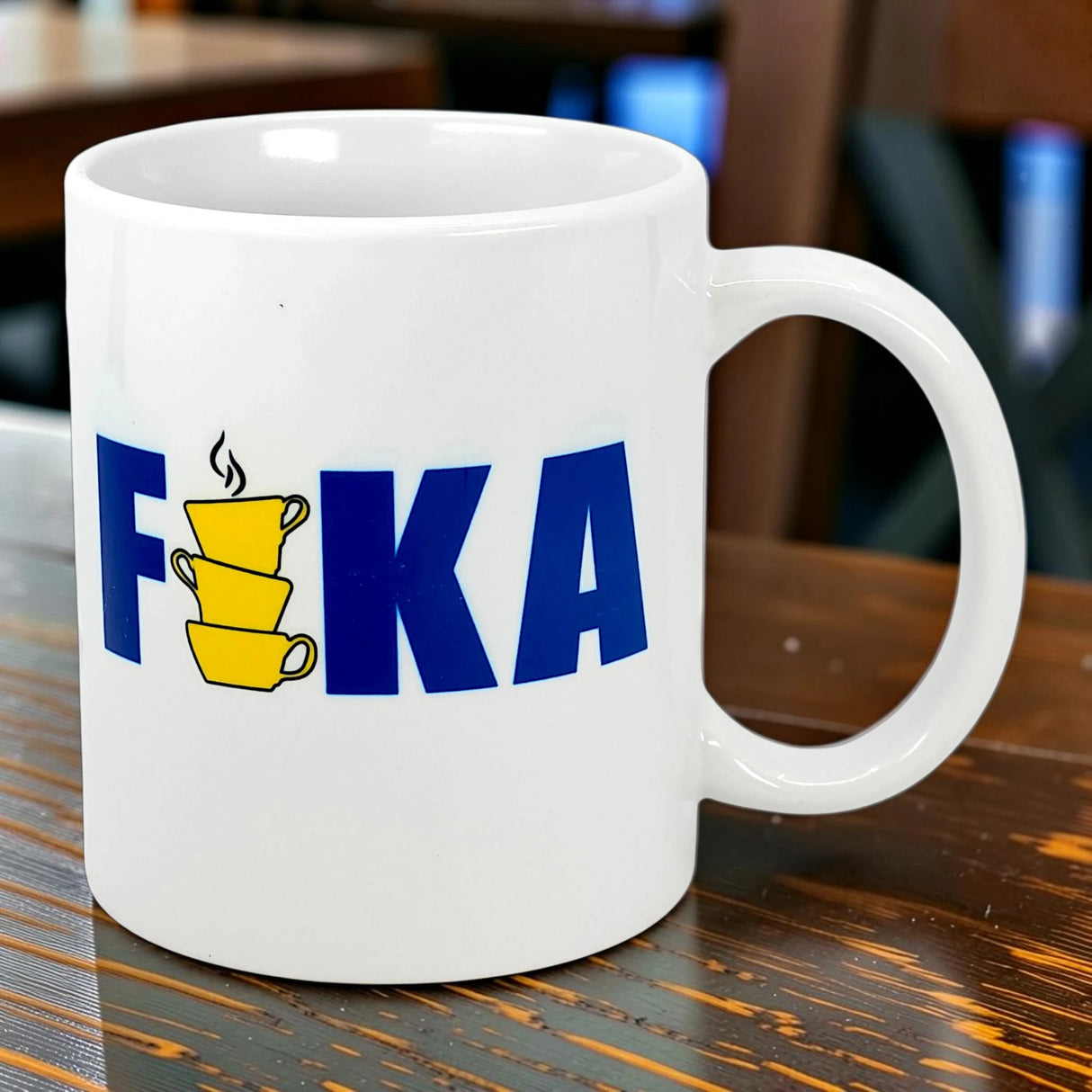The Swedish Gift Store’s 11 oz ceramic mug features “FIKA” in bold blue, with three stacked yellow cups for the “I,” echoing the Swedish flag and classic Fika charm.