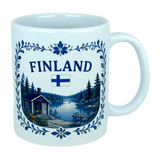 The Nordic Wholesale Mug: Finland Lakeside Cabin Ceramic Mug (11 oz Capacity) is a white Finnish ceramic mug decorated with the Finnish flag and an illustration of a Nordic lakeside cabin nestled among trees, all bordered by an elegant blue floral design—making it an ideal gift to celebrate Finnish heritage.