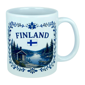 The Nordic Wholesale Mug: Finland Lakeside Cabin Ceramic Mug (11 oz Capacity) is a white Finnish ceramic mug decorated with the Finnish flag and an illustration of a Nordic lakeside cabin nestled among trees, all bordered by an elegant blue floral design—making it an ideal gift to celebrate Finnish heritage.