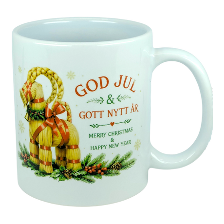The Nordic Wholesale Mug: God Jul Yule Goat Ceramic Mug (11 oz Capacity) is a white mug decorated with a traditional Swedish Julbock—the straw Scandinavian Yule Goat—embellished with red ribbons and festive greenery. The mug features the greeting "God Jul & Gott Nytt År" in Swedish and its English translation, "Merry Christmas & Happy New Year.