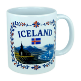 Celebrate Icelandic heritage with the Nordic Wholesale Mug: Iceland Church Mountain Ceramic Mug (11 oz Capacity). This white mug features the “ICELAND” text, the Icelandic flag, and a scenic illustration of mountains, a black church, and water framed by a floral border—a perfect gift that beautifully captures the Nordic landscape.