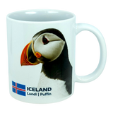 This 11 oz ceramic coffee mug from Nordic Wholesale, the "Mug: Iceland National Animal Puffin," features a photo of an Icelandic puffin alongside the Icelandic flag, with "ICELAND Lundi | Puffin" printed below the image—making it the perfect Nordic wildlife mug for nature lovers.