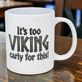 The Swedish Gift Store’s 11 oz white ceramic mug features “It’s Too Viking Early For This” in bold black text, displayed on a wooden table.