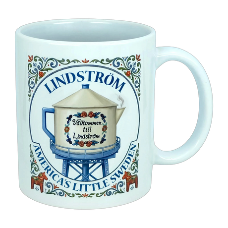 Introducing the Nordic Wholesale Mug: Lindstrom America's Little Sweden Ceramic Coffee Mug (11 oz)—featuring a charming decorative design with a water tower labeled "Välkommen till Lindström," surrounded by floral motifs inspired by Scandinavian folk art and the phrase "Lindstrom, America’s Little Sweden." A perfect mug for celebrating your Swedish heritage.