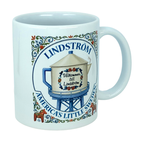 The Mug: Lindstrom America's Little Sweden Ceramic Coffee Mug (11 oz) by Nordic Wholesale features the phrase “Lindström: America's Little Sweden” and an illustration of a water tower labeled “Välkommen till Lindström,” all beautifully accented with Scandinavian folk art floral designs and traditional red Dala horses—a charming Swedish heritage piece for any mug collection.