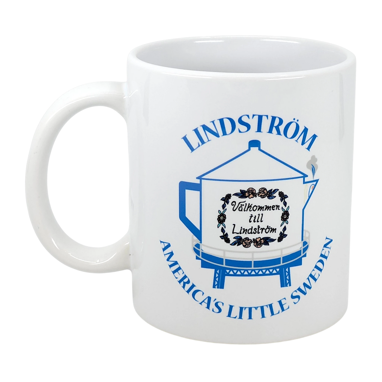 The Swedish Gift Store’s 11 oz ceramic mug features blue "America's Little Sweden" text, the Lindstrom Coffee Pot Water Tower with a “Välkommen till Lindström” sign, and decorative designs—a perfect Chisago Lakes souvenir.
