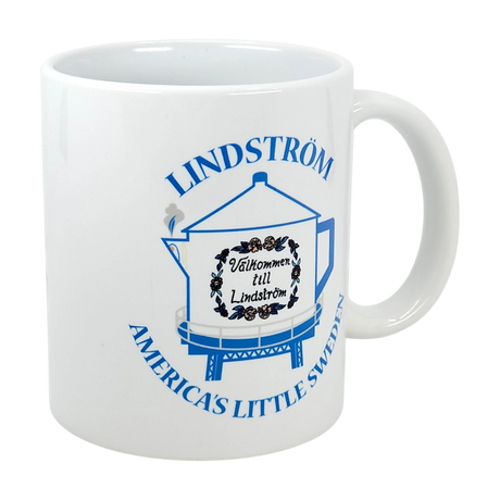 Nordic Wholesale's 11 oz ceramic mug features a blue outline of the Lindstrom Coffee Pot Water Tower, "Välkommen till Lindström" text, floral accents, and "LINDSTRÖM AMERICA'S LITTLE SWEDEN"—the perfect Chisago Lakes souvenir.
