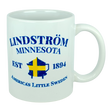 This 11 oz white ceramic mug from Nordic Wholesale features blue text that reads "Lindstrom Minnesota EST 1894 America’s Little Sweden," along with a yellow and blue Swedish flag shaped like the state of Minnesota. The perfect mug for anyone proud of their Lindstrom roots and Swedish heritage. Product name: Mug: Lindstrom Minnesota America's Little Sweden Ceramic Mug (11 oz Capacity).