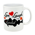 The Mug: Live, Laugh, Lutefisk | 11oz Ceramic Mug by Nordic Wholesale features a black script phrase, three red hearts, and a black fish silhouette—an ideal Scandinavian humor mug or lutefisk gift with Nordic charm.
