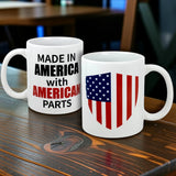 Two white mugs rest on a wooden table: one features an American flag shield, while the other is the Swedish Gift Store's "Mug: Made in America with American Parts Ceramic Mug (11 oz)" with bold black and red text.