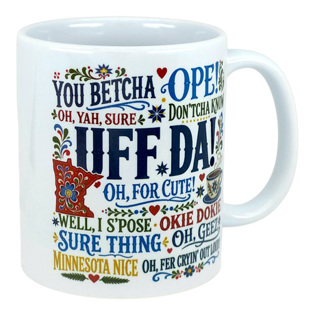 White mug with “Uff da!” and “You betcha” printed in colorful letters, surrounded by floral patterns.