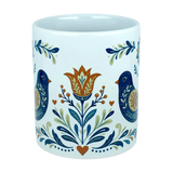 Introducing the Mug: Nordic Folk Art Birds Ceramic Mug (11 oz Capacity) by Nordic Wholesale—an elegant white ceramic mug adorned with a symmetrical folk art motif featuring two blue birds, a central orange and yellow flower, leafy accents, and delicate orange hearts. Ideal for anyone who loves the timeless appeal of Scandinavian design.