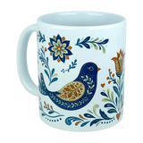 The Nordic Wholesale Mug: Nordic Folk Art Birds Ceramic Mug (11 oz Capacity) is a white ceramic mug with a handle, decorated with a blue and gold folk art bird surrounded by floral and leafy patterns in shades of blue, green, gold, and orange—bringing the charm of Scandinavian design inspired by traditional Nordic rosemaling to your drinkware collection.