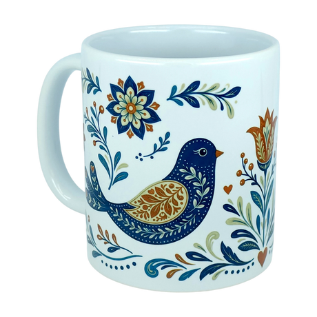 The Nordic Wholesale Mug: Nordic Folk Art Birds Ceramic Mug (11 oz Capacity) is a white ceramic mug with a handle, decorated with a blue and gold folk art bird surrounded by floral and leafy patterns in shades of blue, green, gold, and orange—bringing the charm of Scandinavian design inspired by traditional Nordic rosemaling to your drinkware collection.