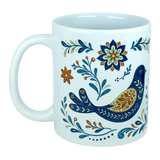 The Nordic Wholesale Mug: Nordic Folk Art Birds Ceramic Mug (11 oz Capacity) features a white ceramic design decorated with a Scandinavian-inspired blue and gold folk-art bird, surrounded by intricate blue, gold, and orange floral and leafy patterns.
