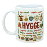 White ceramic coffee cup with colorful Nordic illustrations and visible words including “Hygge,” “cozy,” and “warmth.”.
