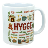 White ceramic mug with “HYGGE” in bold red on the front, surrounded by smaller Scandinavian words including happiness, warmth, and relaxation.