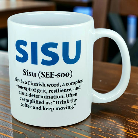 The Nordic Wholesale Mug: Sisu Finnish Word Definition Ceramic Mug (11 oz) is a white mug featuring the definition of "Sisu," a Finnish word meaning grit, resilience, and stoic determination, along with the example: "Drink the coffee and keep moving.
