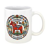 The "Sverige Dala Häst" Mug by Swedish Gift Store features a red Dala horse framed by a Swedish folk art wreath, with “Sverige” and “Dalahäst” stylishly displayed above and below the design. 11 oz ceramic.
