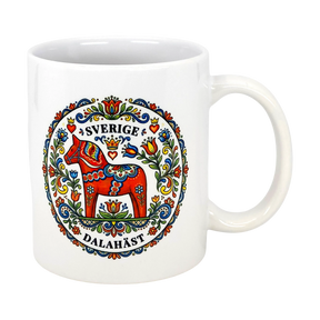 The "Sverige Dala Häst" Mug by Swedish Gift Store features a red Dala horse framed by a Swedish folk art wreath, with “Sverige” and “Dalahäst” stylishly displayed above and below the design. 11 oz ceramic.