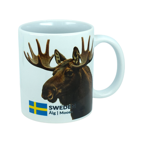The Mug: Sweden Älg Moose Ceramic Mug (11 oz) by Nordic Wholesale features a white ceramic design adorned with a moose head, the Swedish flag, and the text "SWEDEN Älg | Moose" on the side. This stylish mug is a charming addition to any Scandinavian kitchen, capturing the essence of Nordic nature in your daily routine.