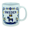 The Nordic Wholesale Mug: Sweden Dala Horse Ceramic Mug (11 oz Capacity) features blue and yellow floral designs, the word "SWEDEN," a small Swedish flag, and a traditional blue Dala horse above a silhouette of buildings—beautifully celebrating Swedish heritage in this charming Scandinavian folk mug.