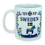 Celebrate your love for Swedish heritage with the Nordic Wholesale Mug: Sweden Dala Horse Ceramic Mug (11 oz Capacity). This beautifully crafted white ceramic mug showcases blue and yellow floral designs, the word "Sweden," a Swedish flag, and a striking blue Dala horse on the front, perfectly capturing Scandinavian folk tradition and charm—an ideal addition to any collection.