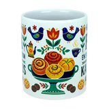 Celebrate Swedish coffee traditions with the Mug: Fika — "En Svensk Tradition Kaffepaus" Swedish Fika Traditions Wraparound Ceramic Mug (11 oz) by Nordic Wholesale. This white ceramic mug is adorned with vibrant folk art depicting birds, flowers, a pedestal of pastries, and cookies in bright patterns and warm hues. Its festive and cozy design makes it an ideal gift for those who cherish Swedish traditions or a charming Scandinavian coffee mug for elevating your daily fika rituals.