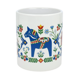The Nordic Wholesale Mug: Swedish Folk Art — Blue Dala Horse, Church & Red House is an 11oz ceramic mug adorned with a vibrant folk art design featuring a blue Dala horse, colorful flowers, a charming red house, and decorative patterns in red, green, and yellow—a perfect addition to bring Swedish charm to your coffee or tea routine.