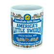 The Nordic Wholesale Mug: Swedish Gift Store America's Little Sweden Wraparound Ceramic Mug (11 oz) features vibrant, colorful designs including "Swedish Gift Store," "America's Little Sweden," "Lindström, MN," "SwedishGiftStore.com," and a yellow Dala horse icon on a blue background—making it the perfect Swedish-American mug for celebrating your heritage.