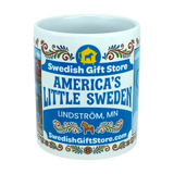The Nordic Wholesale Mug: Swedish Gift Store America's Little Sweden Wraparound Ceramic Mug (11 oz) features vibrant, colorful designs including "Swedish Gift Store," "America's Little Sweden," "Lindström, MN," "SwedishGiftStore.com," and a yellow Dala horse icon on a blue background—making it the perfect Swedish-American mug for celebrating your heritage.