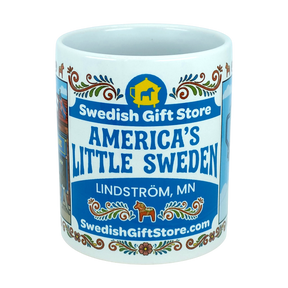 The Nordic Wholesale Mug: Swedish Gift Store America's Little Sweden Wraparound Ceramic Mug (11 oz) features vibrant, colorful designs including "Swedish Gift Store," "America's Little Sweden," "Lindström, MN," "SwedishGiftStore.com," and a yellow Dala horse icon on a blue background—making it the perfect Swedish-American mug for celebrating your heritage.