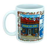 The Nordic Wholesale "Mug: Swedish Gift Store America's Little Sweden Wraparound Ceramic Mug" (11 oz) is a white ceramic mug adorned with an illustration of a Swedish gift store, complete with Scandinavian flags above the entrance and floral decorative borders along the edge.