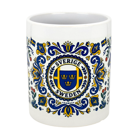 The Nordic Wholesale Mug: Swedish Icons & Dala Horse Folk Art Ceramic Mug (11 oz) features blue and yellow folk art patterns, a triple crown emblem with "Sverige Sweden," decorative flourishes, and a subtle Dala horse motif.
