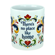 The Nordic Wholesale "There's No Place Like Home" Rosemaling Ceramic Mug (11 oz) is a white ceramic coffee mug featuring vibrant Scandinavian folk art-inspired floral designs and "There's no place like home" written in blue on the front.